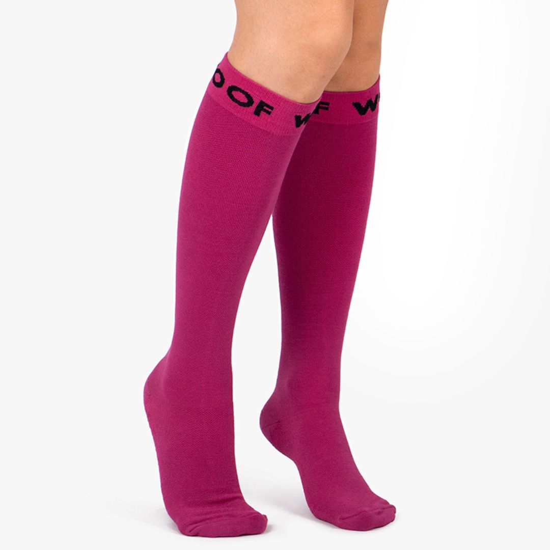 Nurse wearing solid magenta pink knee-high compression socks with dark top cuff branding.